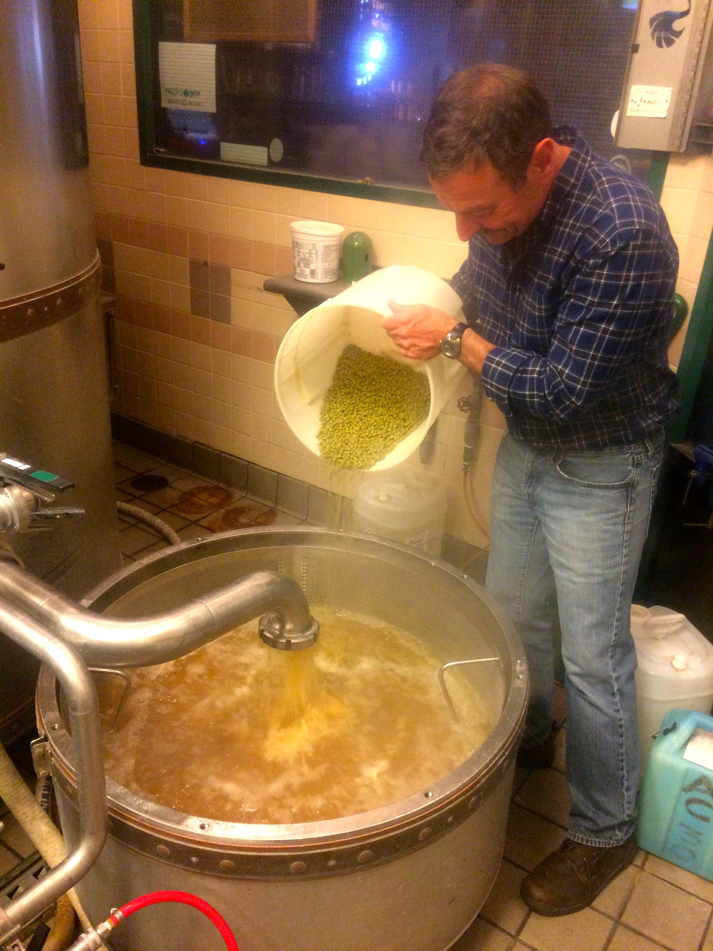 Peter Bowers adding hops to the boil kettle while helping design the Patient Angler Pale Ale recipe